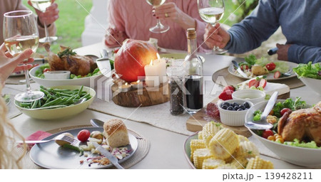 Clinking four adults in sweaters raising wine glasses at porch table, with lit slab and apple 139428211