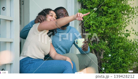 Sitting couple leaning on front porch step, with light green mug, blue sweater, cream top, shrub 139428212