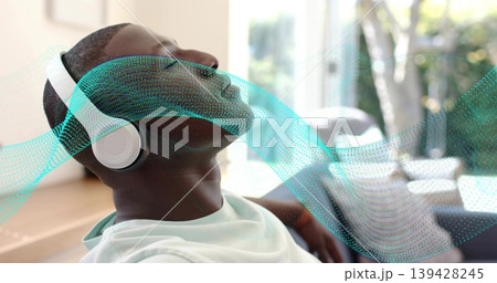Reclining man wearing white tee and white headphones listening at home near window, with teal wave Reclining man wearing white tee and white headphones listening at home near window, with teal wave 139428245