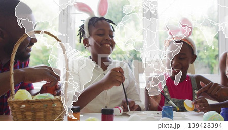 Painting family at home table decorating eggs, boy in white shirt wearing bunny ears, paint jars Painting family at home table decorating eggs, boy in white shirt wearing bunny ears, paint jars 139428394