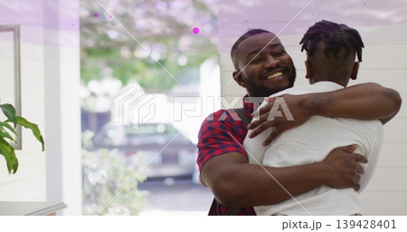 Embracing father and son in home entryway, wearing plaid shirt and white T-shirt, near open doorway Embracing father and son in home entryway, wearing plaid shirt and white T-shirt, near open doorway 139428401