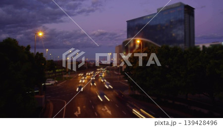 Showing multi-lane roadway with moving cars and light trails from bridge at dusk, with glass tower Showing multi-lane roadway with moving cars and light trails from bridge at dusk, with glass tower 139428496