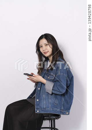 椅子に座って携帯電話を操作する若い女性 椅子に座って携帯電話を操作する若い女性 139428798