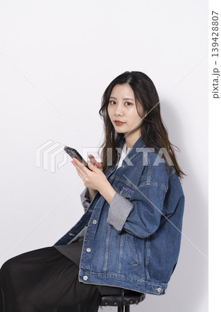 椅子に座って携帯電話を操作する若い女性 椅子に座って携帯電話を操作する若い女性 139428807