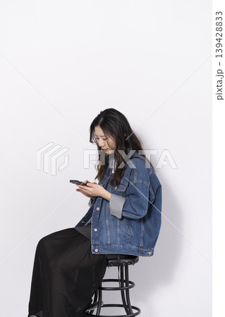 椅子に座ってスマホを操作する女性 椅子に座ってスマホを操作する女性 139428833