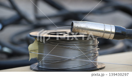 Welding wire spool and MIG gun nozzle ready for metal fabrication work 139430297
