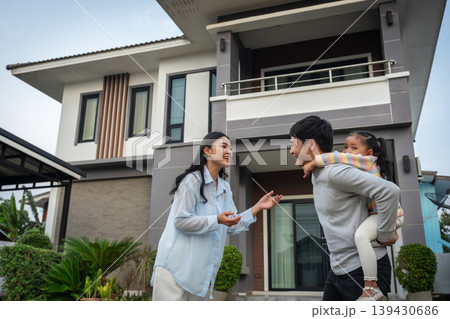 happy family, cheerful child girl piggy back on fatherwith mother while standing in front of their house happy family, cheerful child girl piggy back on fatherwith mother while standing in front of their house 139430686