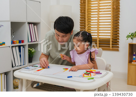 Caption/Description: father and child girl drawing and painting with colorful oil pastels on paper Caption/Description: father and child girl drawing and painting with colorful oil pastels on paper 139430730