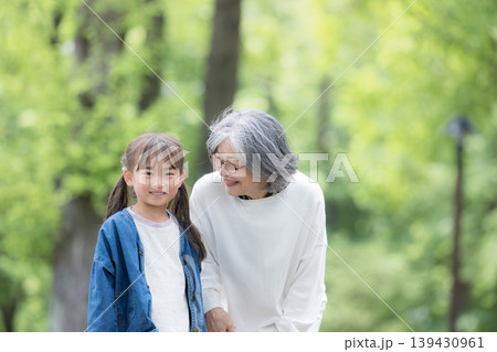 春の新緑の公園で遊ぶおばあちゃんと寄り添う笑顔の孫娘のクローズアップカメラ目線 右にコピースペース 春の新緑の公園で遊ぶおばあちゃんと寄り添う笑顔の孫娘のクローズアップカメラ目線 右にコピースペース 139430961