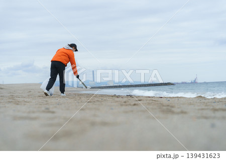 砂浜でゴミ拾いをする人 139431623