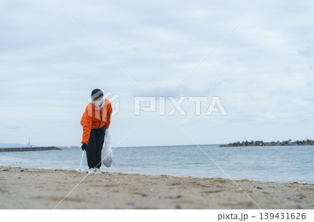 砂浜でゴミ拾いをする人 139431626