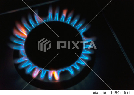 Blue and orange gas flames burning on a kitchen stove burner in the dark Blue and orange gas flames burning on a kitchen stove burner in the dark 139431651