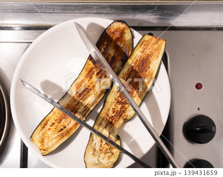 Grilled eggplant slices on a white plate with metal kitchen tongs Grilled eggplant slices on a white plate with metal kitchen tongs 139431659