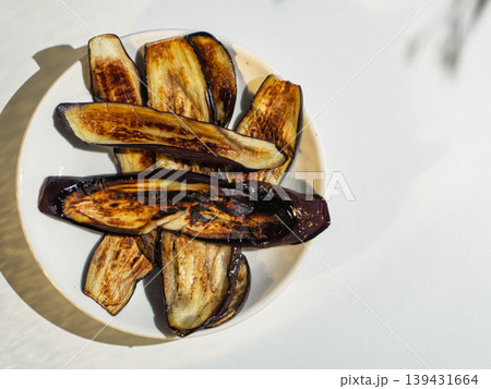 Fried eggplant slices served on a white plate under bright sunlight Fried eggplant slices served on a white plate under bright sunlight 139431664