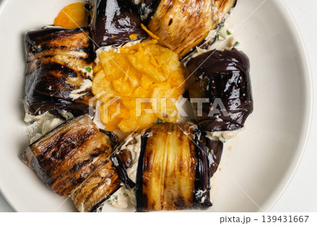 Grilled eggplant rolls with creamy filling and potato chips on a plate Grilled eggplant rolls with creamy filling and potato chips on a plate 139431667