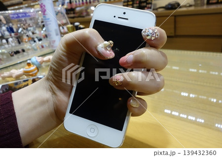 Hand with Glitter Nails Holding iPhone in Store 139432360