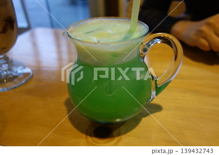 Green Iced Beverage in Glass Pitcher with Straw 139432743