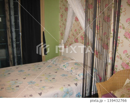 Floral Bed in Cozy Bedroom with Wallpaper and Wicker Chair 139432766