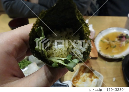 Hand Holding Seaweed-Wrapped Rice Snack with Sprouts 139432804