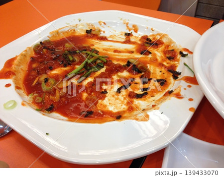 Partially Eaten Dish with Red Sauce and Vegetables on Plate 139433070