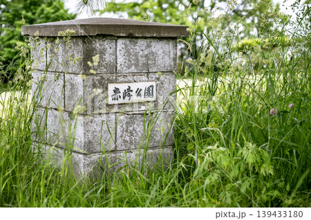 緑の草むらの中に佇む古い公園の名称が書かれた門柱 139433180