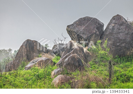 Dramatic Boulders and Lush Greenery Under a Grey Sky in a Serene Natural Landscape, Majestic Rock Formations. Hurulu Eco Park Safari in Sri Lanka. Dramatic Boulders and Lush Greenery Under a Grey Sky in a Serene Natural Landscape, Majestic Rock Formations. Hurulu Eco Park Safari in Sri Lanka. 139433341