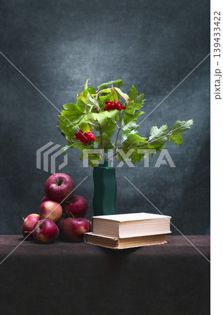 Still life with a red viburnum branch in a vase, ripe apples, and a book Still life with a red viburnum branch in a vase, ripe apples, and a book 139433422