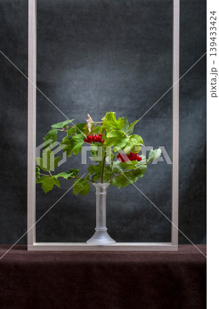 A branch of red viburnum in a vase and a wooden frame A branch of red viburnum in a vase and a wooden frame 139433424
