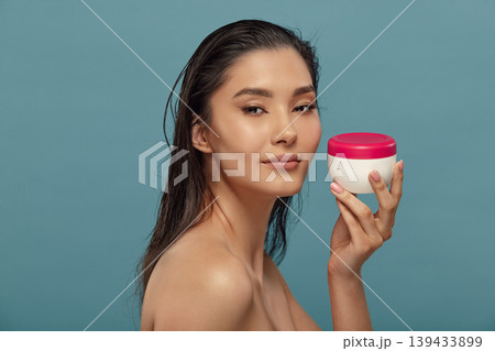 Headshot portrait of asian girl holding round cream jar. Headshot portrait of asian girl holding round cream jar. 139433899