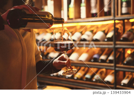 Woman Pouring Red Wine in Cozy Cellar 139433904
