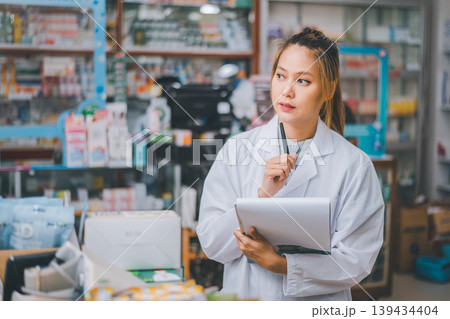 Pharmacist checking Checks Inventory of Medicine, Drugs, Vitamins with tablet and checking patient's prescription in modern pharmacy. Pharmacist checking Checks Inventory of Medicine, Drugs, Vitamins with tablet and checking patient's prescription in modern pharmacy. 139434404