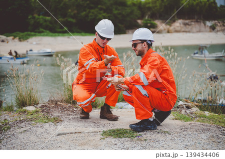 Oil and gas engineers discussing technical data at site near coastal refinery Oil and gas engineers discussing technical data at site near coastal refinery 139434406