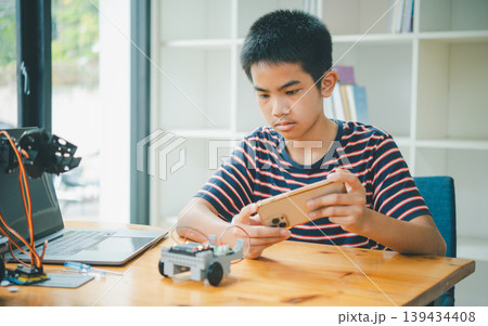 Asian boy learning and studying the work of technology robots.homeschool and science for tech project. playing childhood kids hobby leisure lifestyle people toys robotics technology. Asian boy learning and studying the work of technology robots.homeschool and science for tech project. playing childhood kids hobby leisure lifestyle people toys robotics technology. 139434408