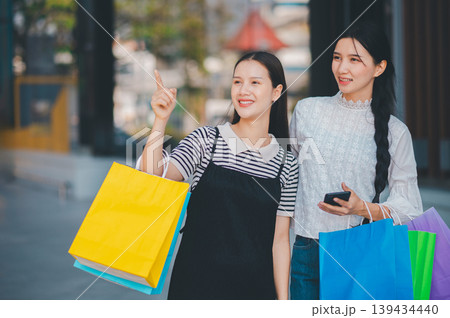 Two women are shopping and one of them is pointing at a cell phone 139434440