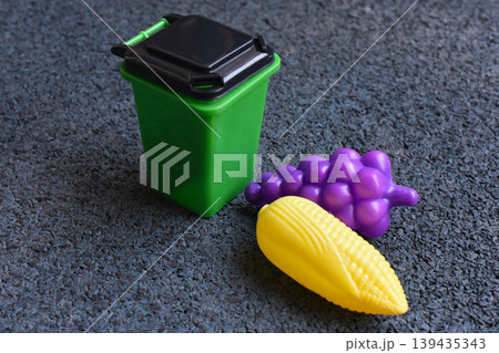 Toy food in a small green bin for play and recycling concepts Toy food in a small green bin for play and recycling concepts 139435343
