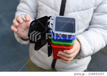 Child holding stacked colorful plastic recycling containers Child holding stacked colorful plastic recycling containers 139435357