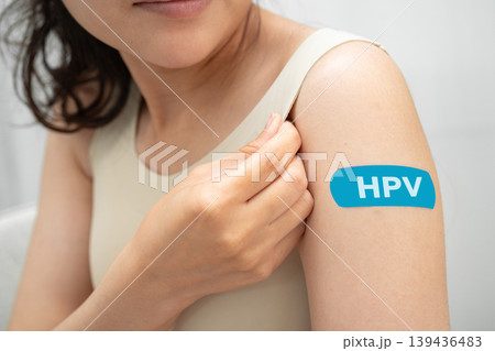 HPV, Human papillomavirus, Asian young woman receiving vaccine with blue bandage. 139436483