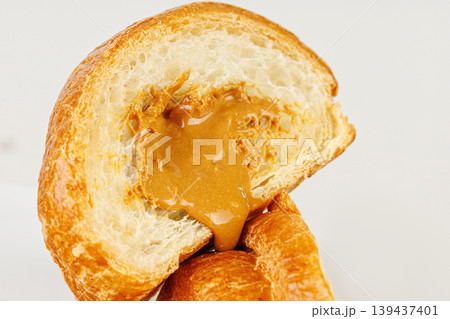 Sliced croissant with caramel condensed milk filling isolated on white. Tasty sweet French pastry. 139437401