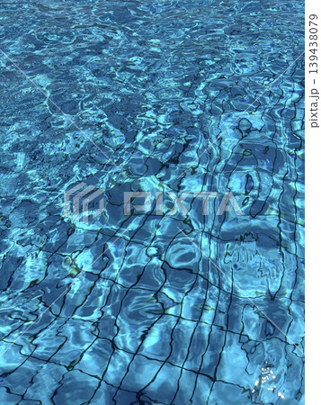 Texture of clear transparent blue water in a swimming pool on a sunny day. Water ripples and sun glare in the pool. 139438079