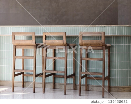 Three wooden bar stools against a tiled counter. Three wooden bar stools against a tiled counter. 139438681