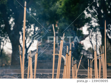 Incense sticks burning in a park during the morning with trees and smoke rising in the air Incense sticks burning in a park during the morning with trees and smoke rising in the air 139439095