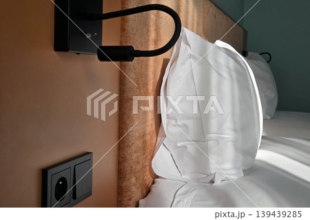Cozy Hotel Bedroom with Modern Wall Light and Soft Pillows for Relaxation and Comfort 139439285