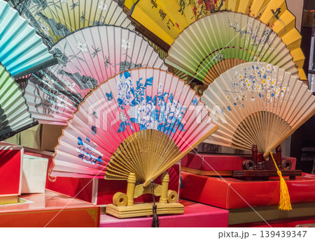 Colorful fans displayed at a market in Asia during the day showcasing traditional designs and craftsmanship Colorful fans displayed at a market in Asia during the day showcasing traditional designs and craftsmanship 139439347