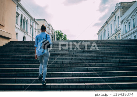 Person walks up large stone staircase in urban environment 139439374