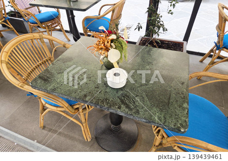 Cozy Outdoor Cafe Seating with Rattan Chairs and Floral Arrangement for Relaxed Dining 139439461