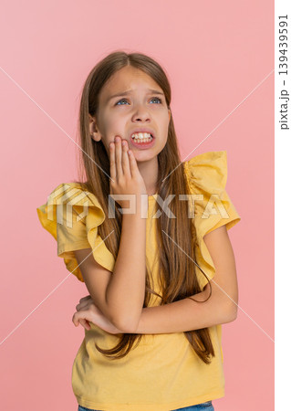 Child girl kid touching cheek in pain suffering from strong toothache expressing sadness discomfort Child girl kid touching cheek in pain suffering from strong toothache expressing sadness discomfort 139439591