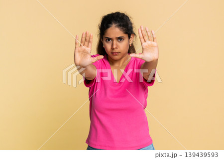 Indian woman raising open palm in stop gesture, looking seriously at camera, expressing prohibition 139439593