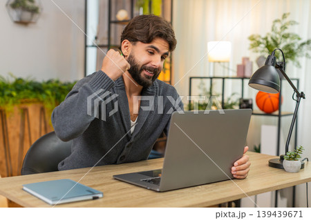 Indian man hits submit on laptop gets project approval smiles fist pump celebrates victory good news 139439671