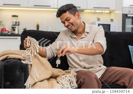 Indian man misplaces keys searches cushions finds keys under blanket laughs with relief and smiles Indian man misplaces keys searches cushions finds keys under blanket laughs with relief and smiles 139439714