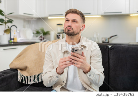 Young man studies online course on smartphone uses headphones listens lecture and sets weekly goal Young man studies online course on smartphone uses headphones listens lecture and sets weekly goal 139439762
